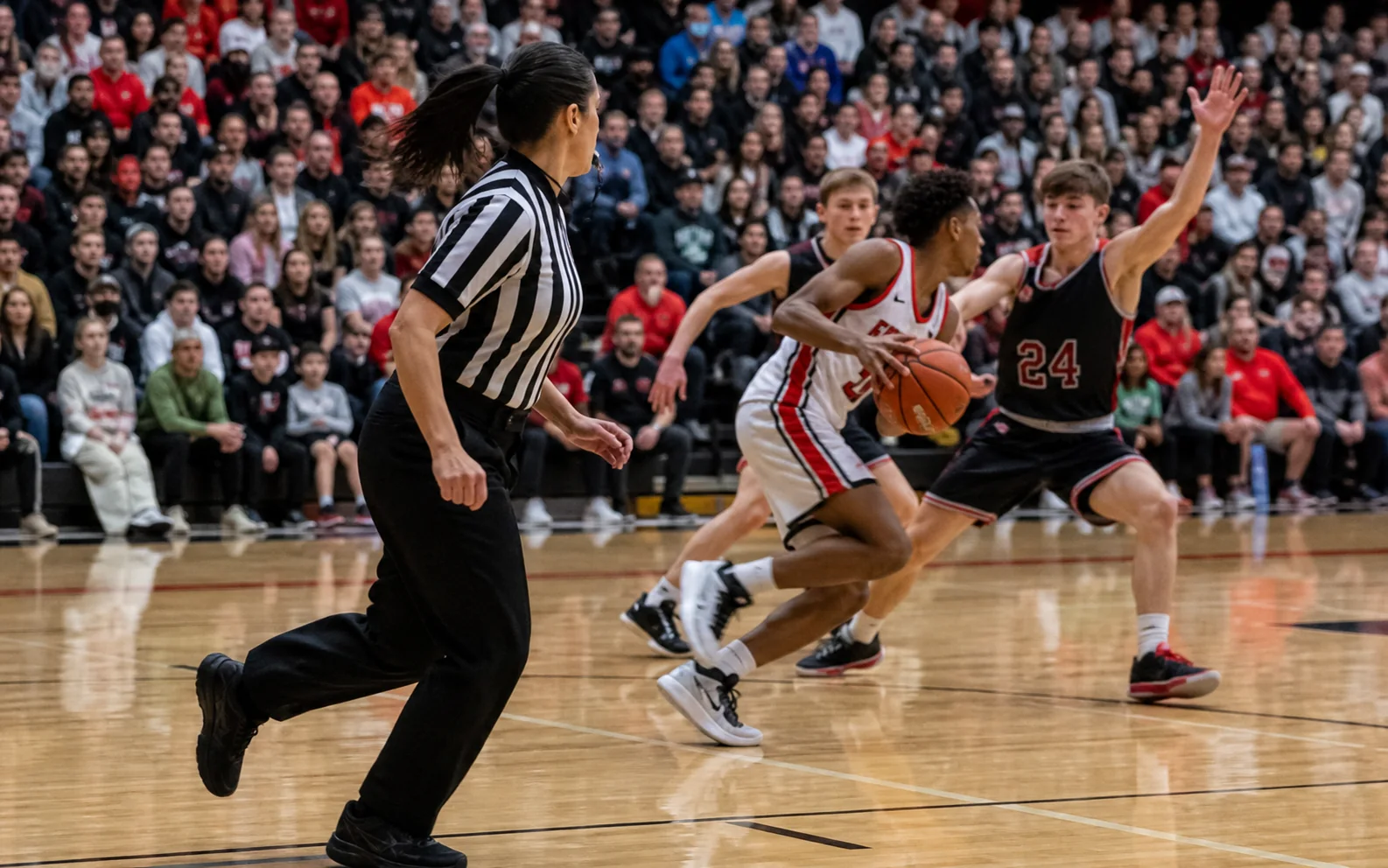 Female high school basketball referee moving with championship play